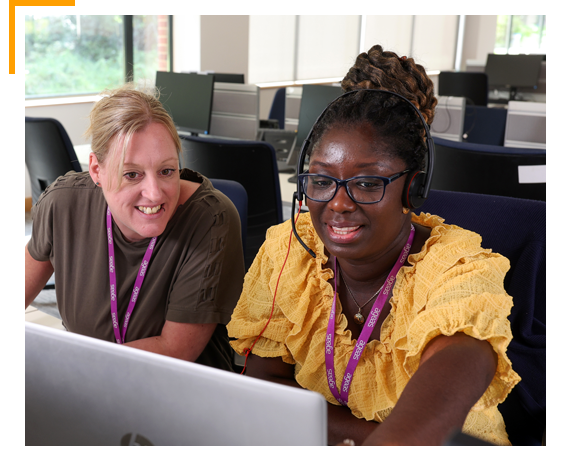 Two colleagues at computer helping each other