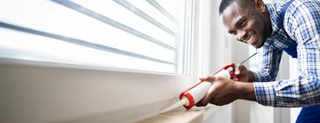 Man puts sealant on windows inside