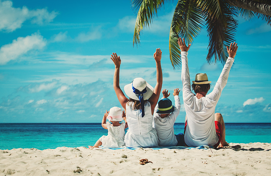 Family sitting on a beach palm tree and bright blue sky