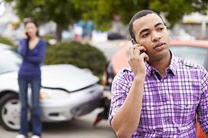 Man on the phone and woman on the phone in the background after a traffic collision