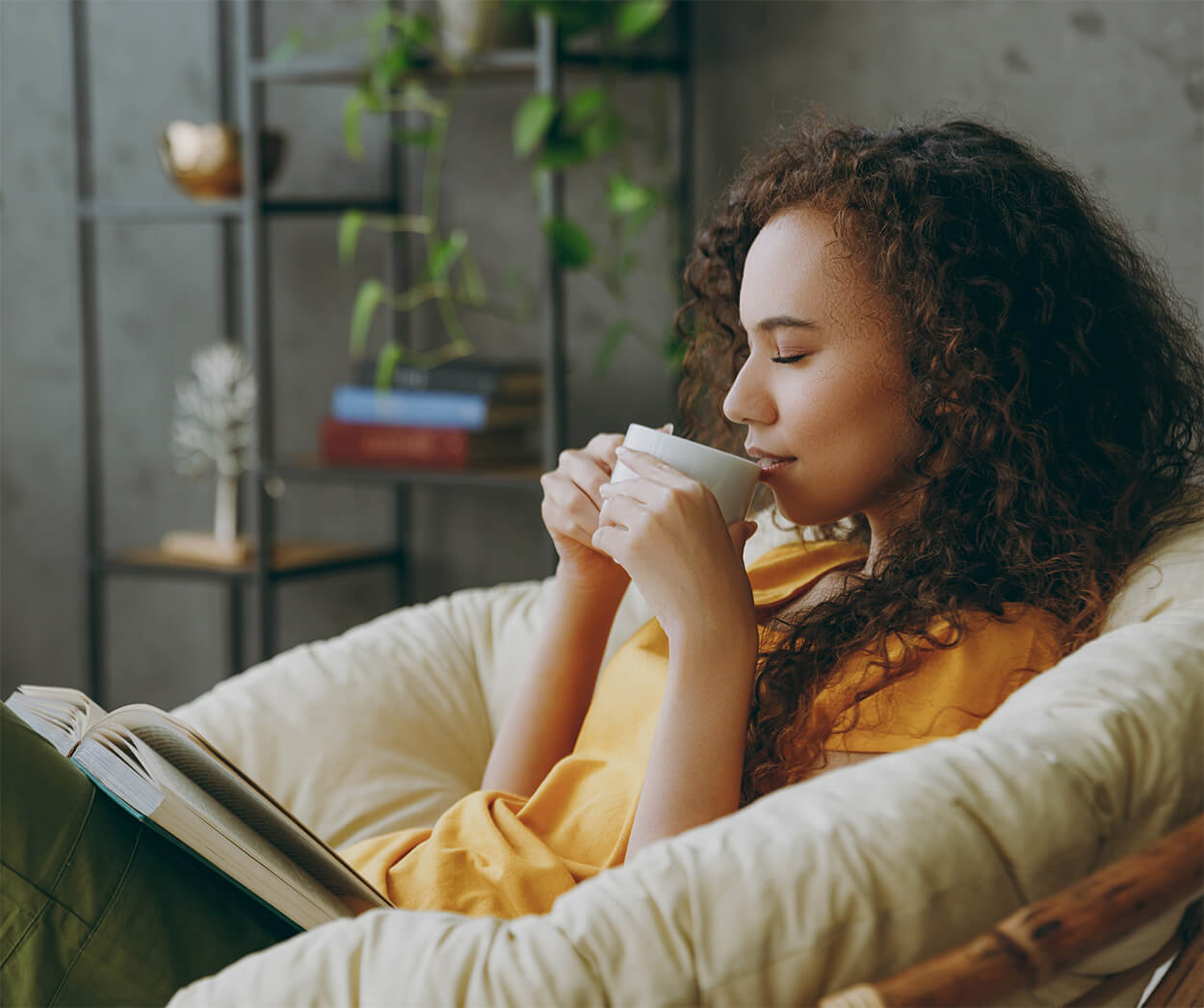 Woman relaxing on sofa with cup of tea and book