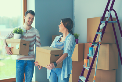 man and woman moving boxes into new home