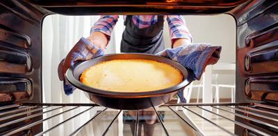 woman taking baked cake out of the oven