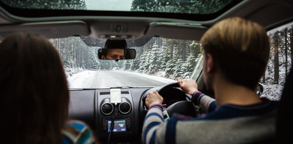 man and woman driving in car listening to christmas music playlist