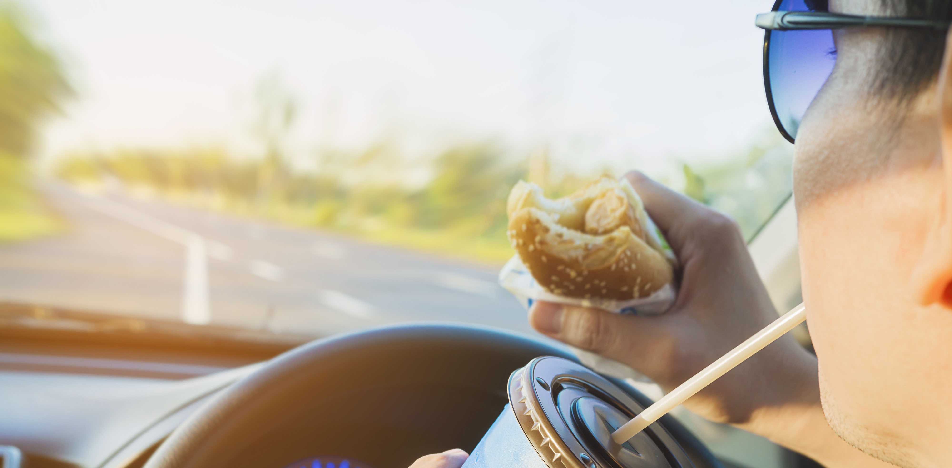 man eating and drinking while driving