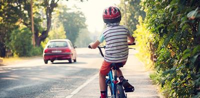 Child riding his bicycle along a main road