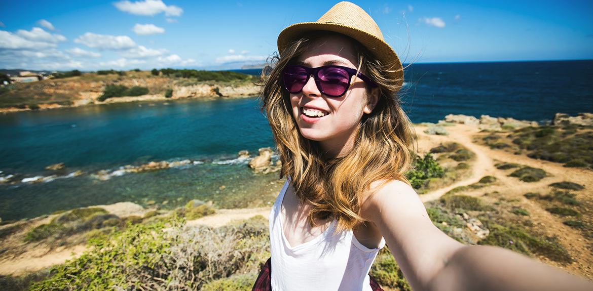 woman taking selfie for social media on sunny holiday