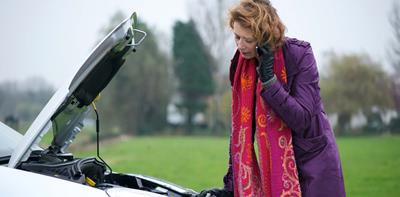 woman on phone looking confused at her car