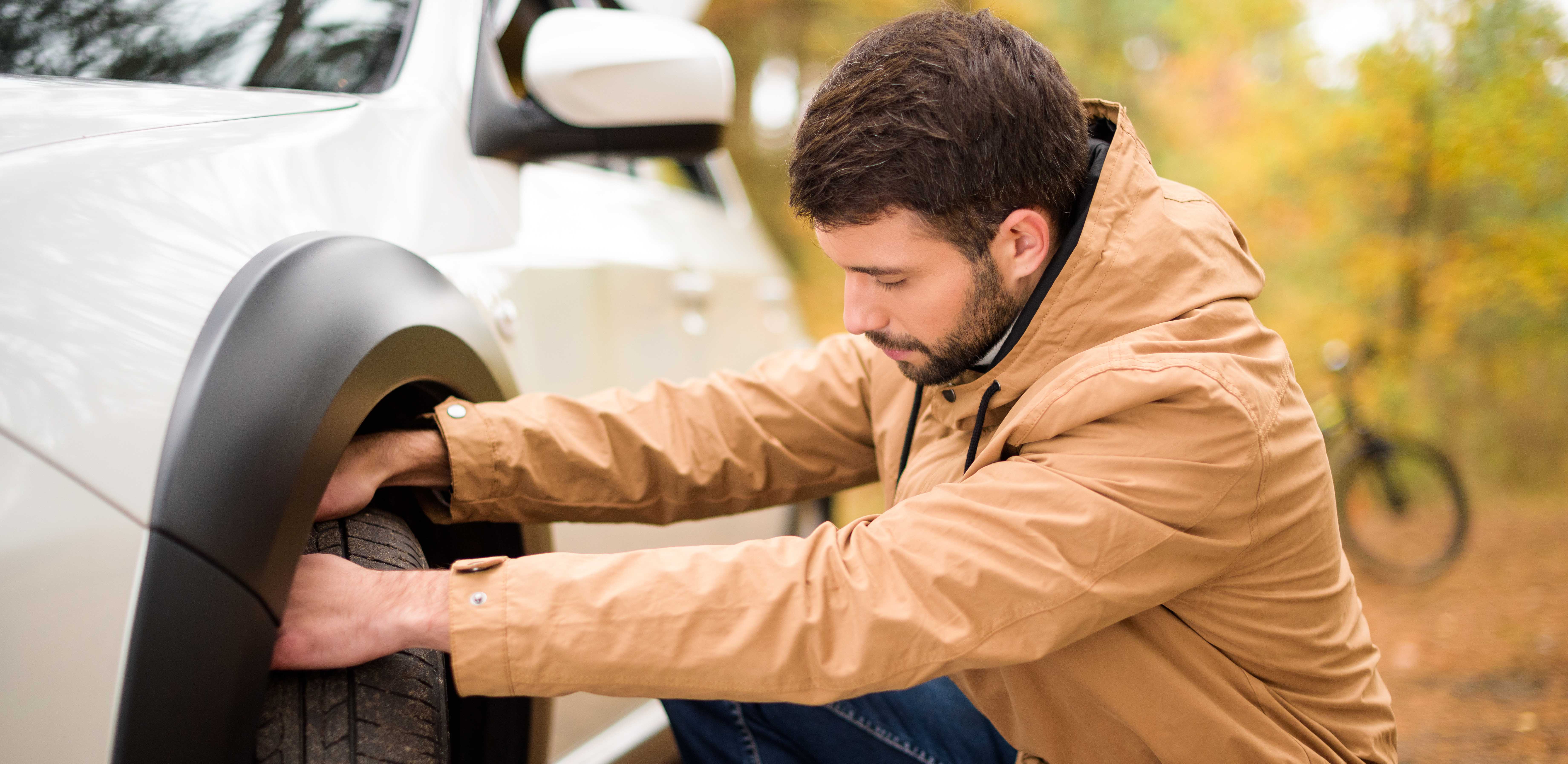 man checking tyre on car