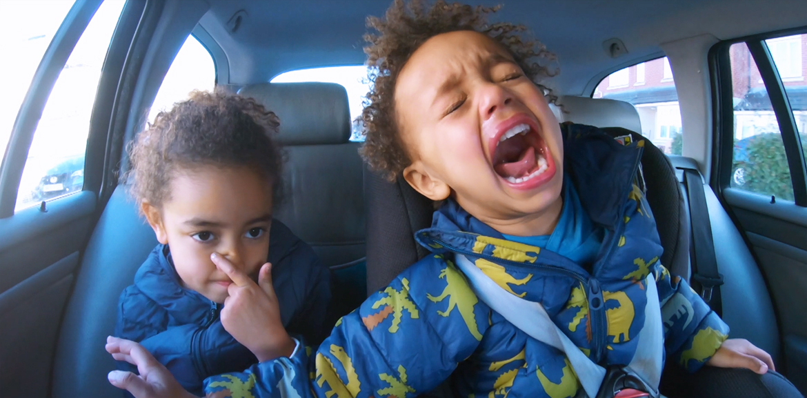 two children arguing and screaming in car seat