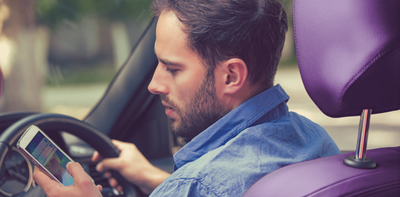 Man driving while checking his phone