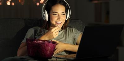 woman watching film laptop headphones popcorn