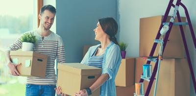 man and woman moving boxes into new home