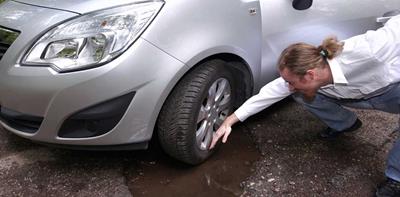 man inspecting car damage after hitting a pothole