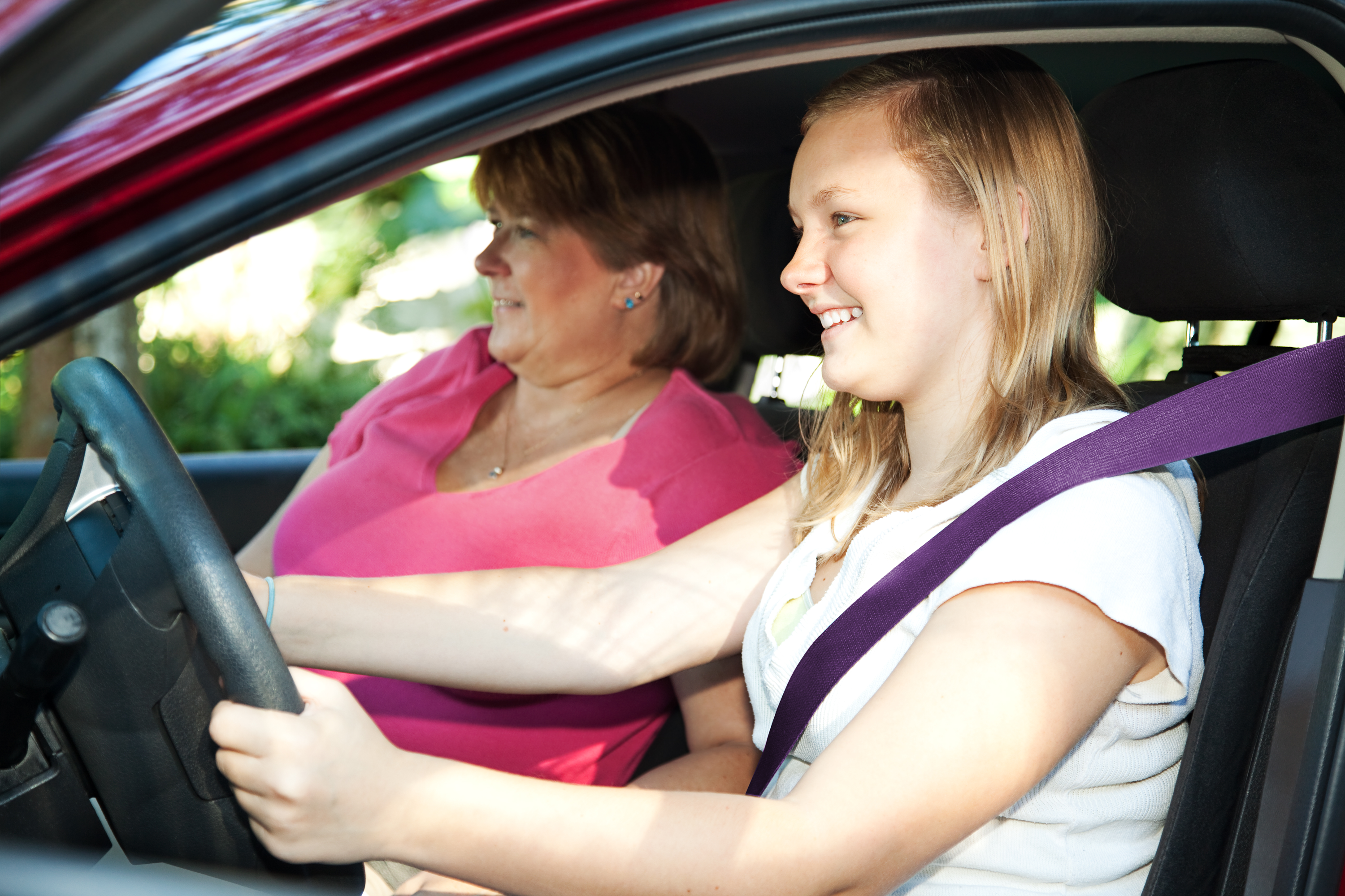 young woman learning to drive with mother next to her