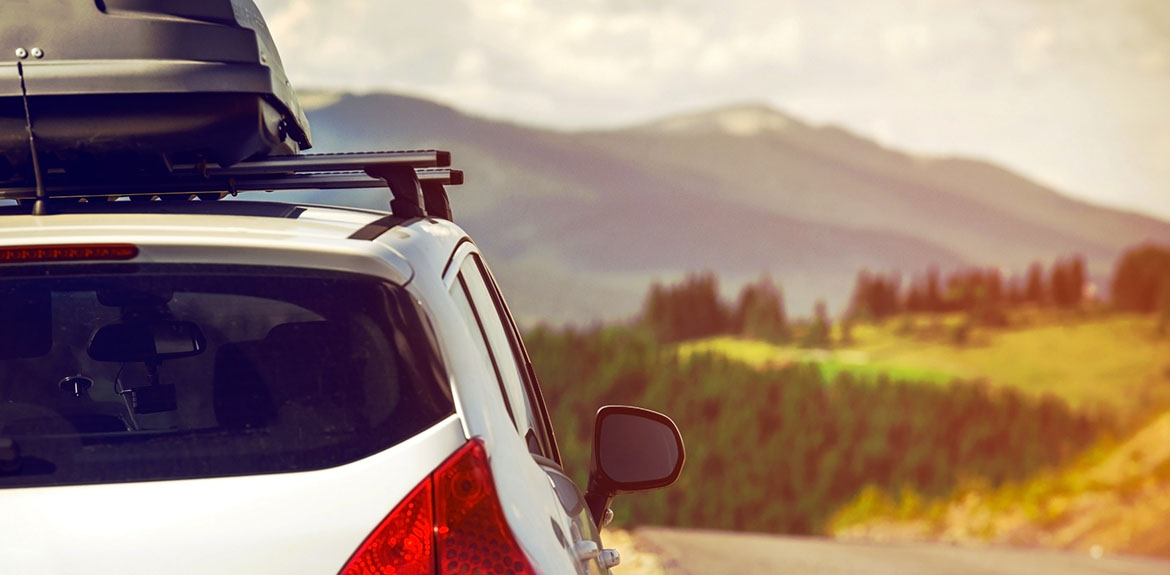 car with roof box driving in countryside during summer