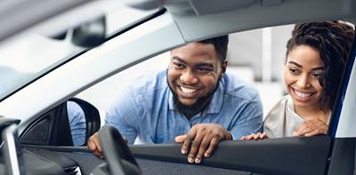 man and woman looking inside car