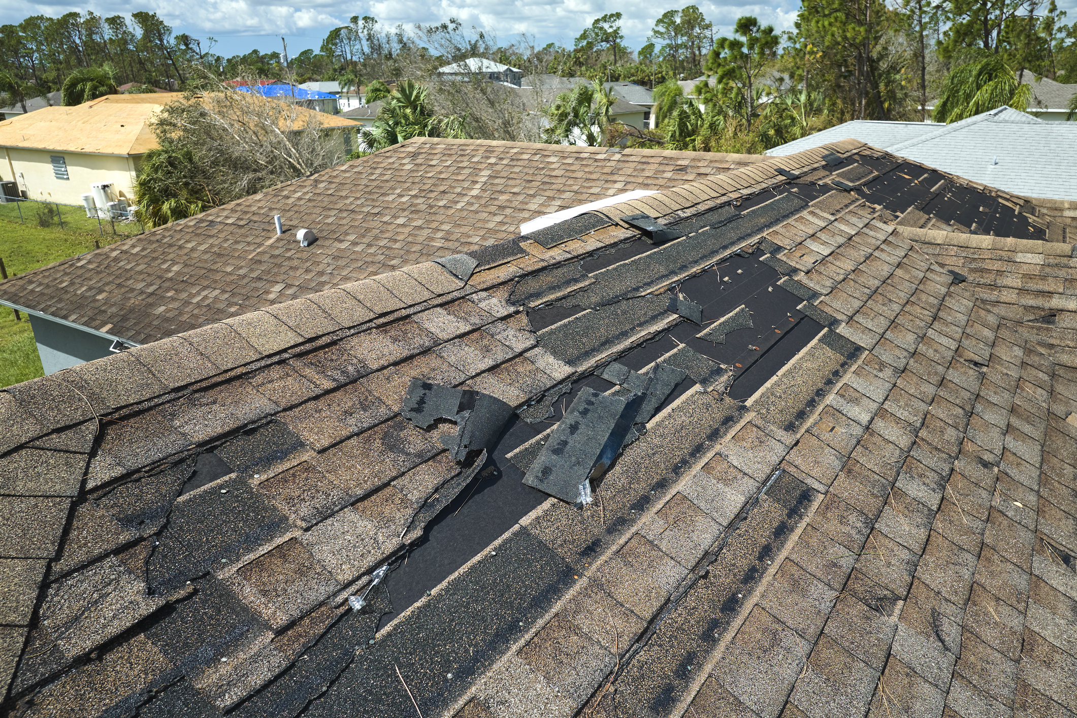 house with a roof that has tiles falling off