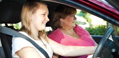 young woman learning to drive with mother next to her